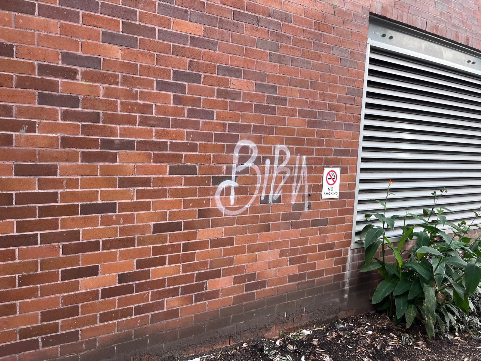 White graffiti tag on brick wall before removal — Northern Beaches Sydney