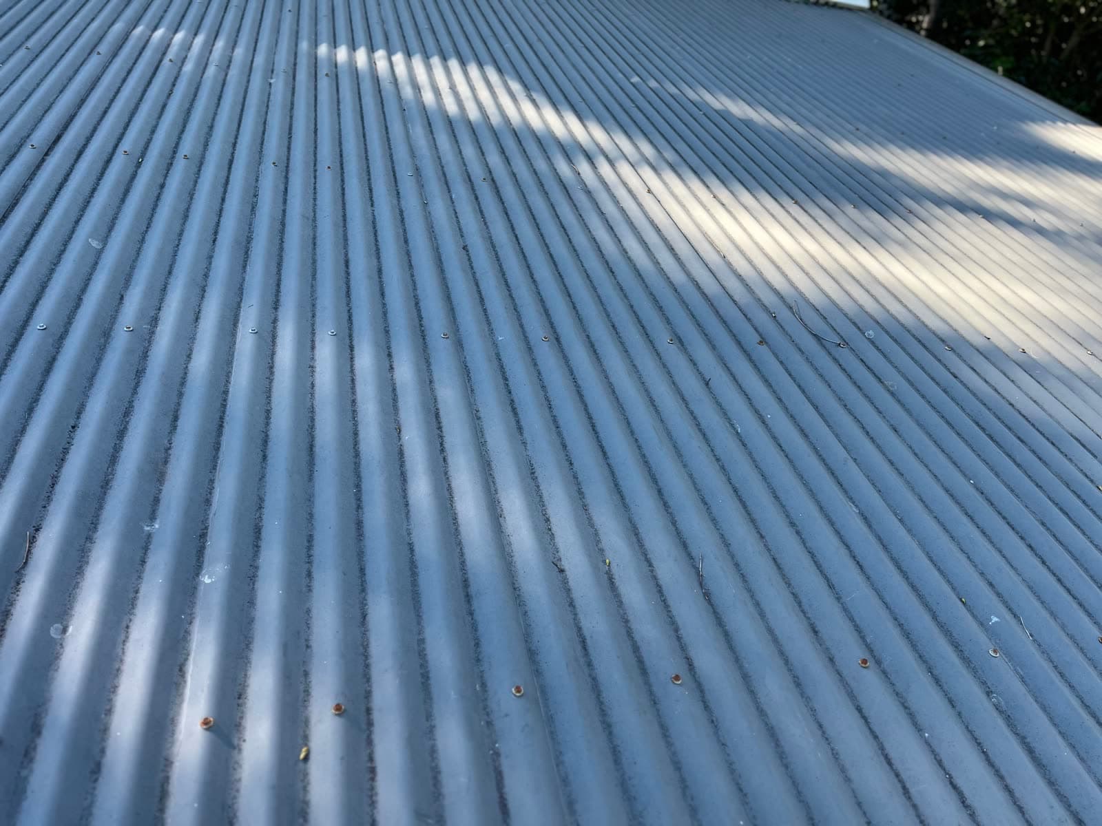 Grimy corrugated metal roof close-up before pressure cleaning